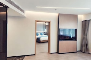 A modern hotel room with a bed, a TV, and a wooden cabinet.
