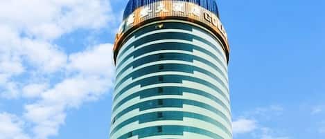 A tall, cylindrical building with a blue glass facade and a dome-like structure on top.