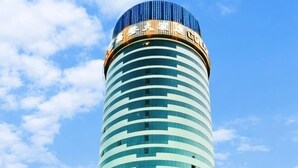 Um edifício alto e cilíndrico com janelas horizontais e topo azulado.