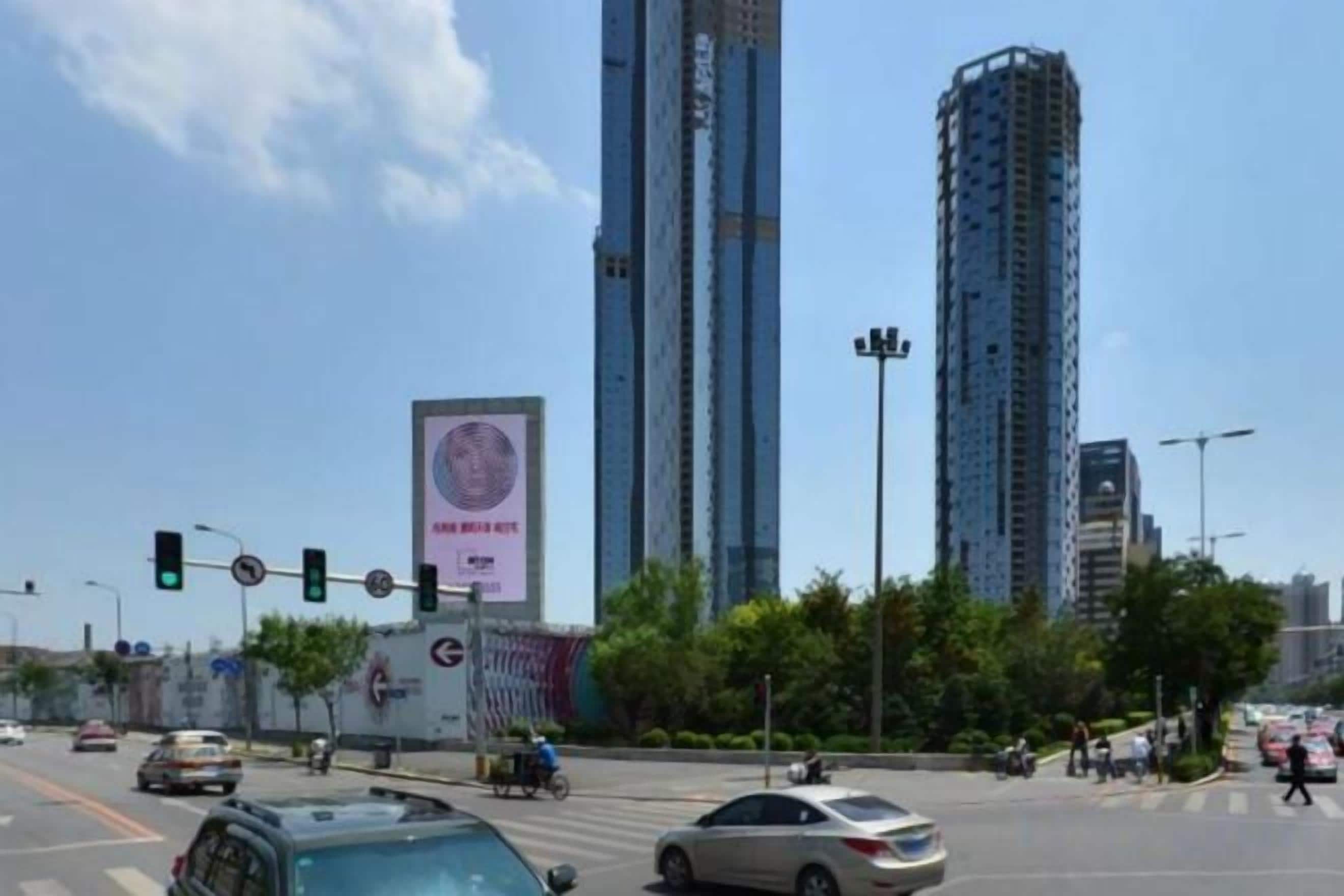 A busy urban intersection with tall buildings, traffic lights, and vehicles.
