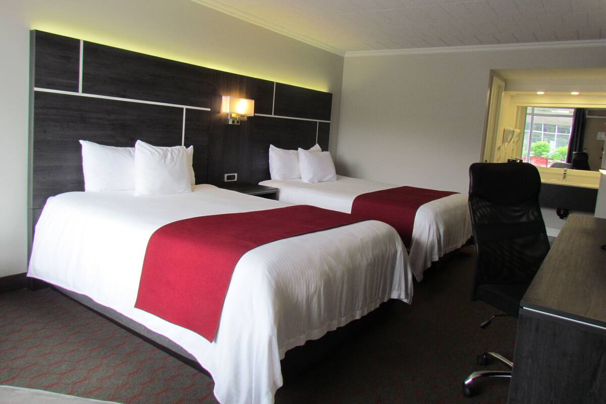 Habitación de hotel con dos camas, un escritorio y una silla.