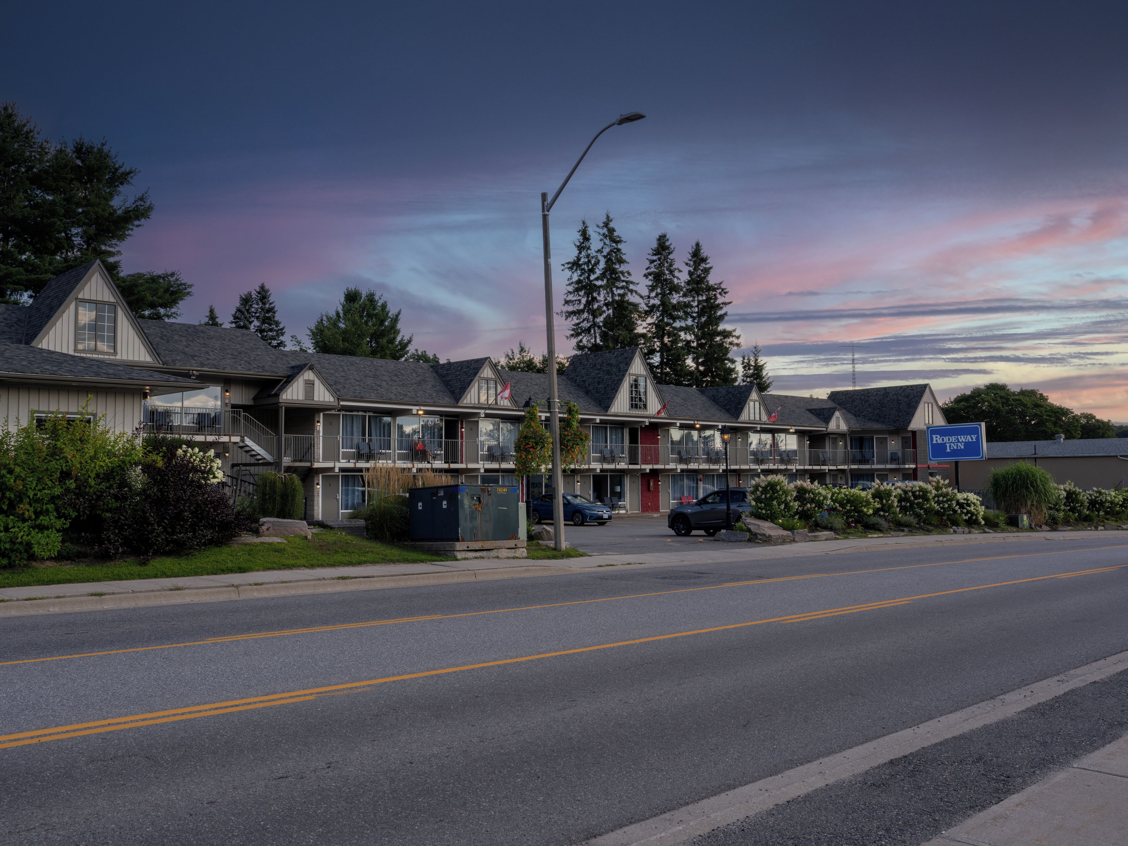 A motel with a two-story structure, a covered parking area, and a street view.