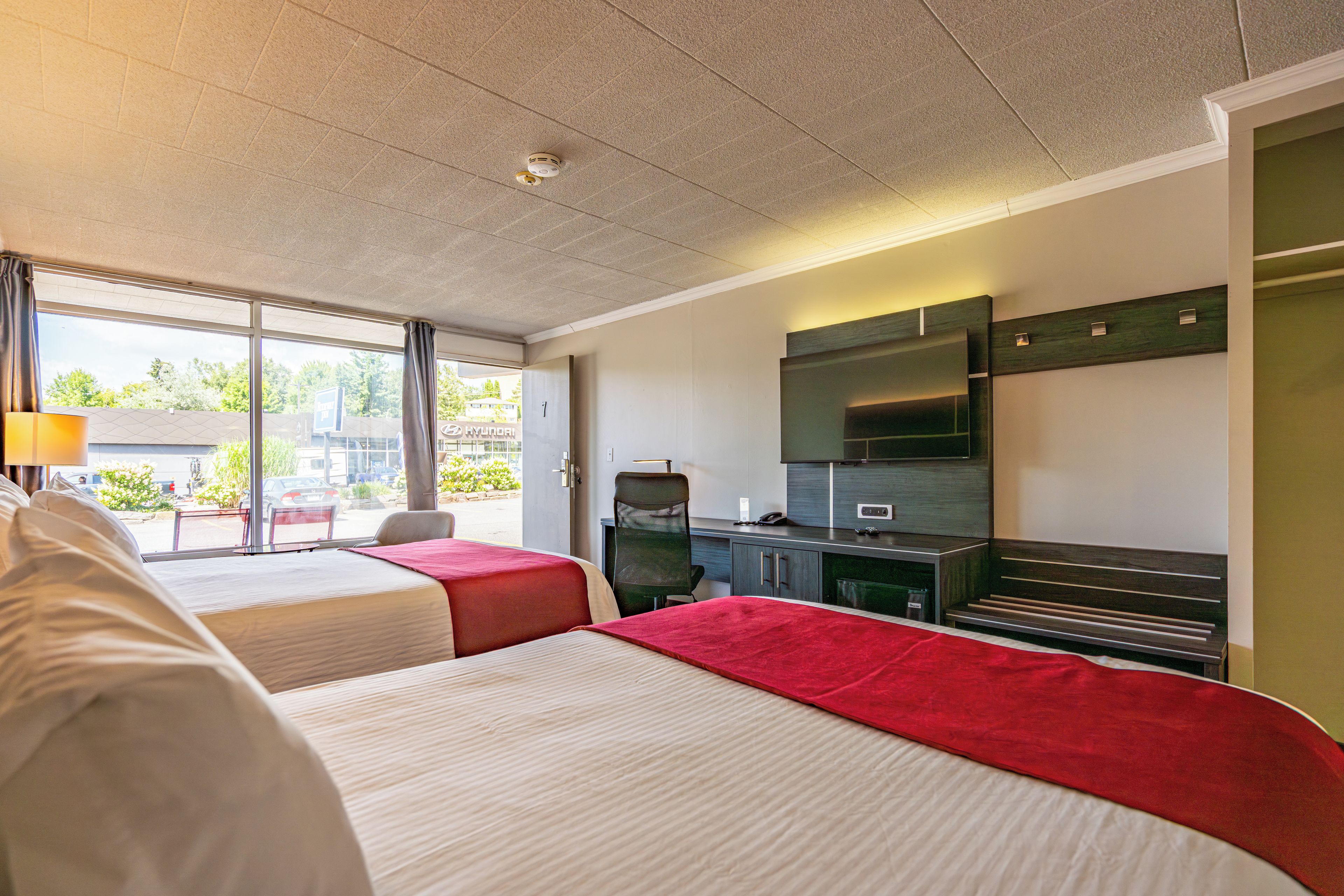 Een hotelkamer met twee bedden, een bureau, een stoel, een televisie en een raam met uitzicht.