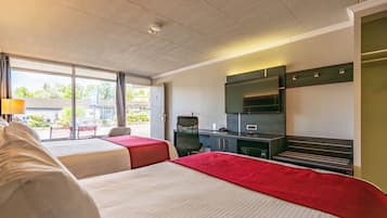 Een hotelkamer met twee bedden, een bureau, een stoel, een televisie en een raam met uitzicht.