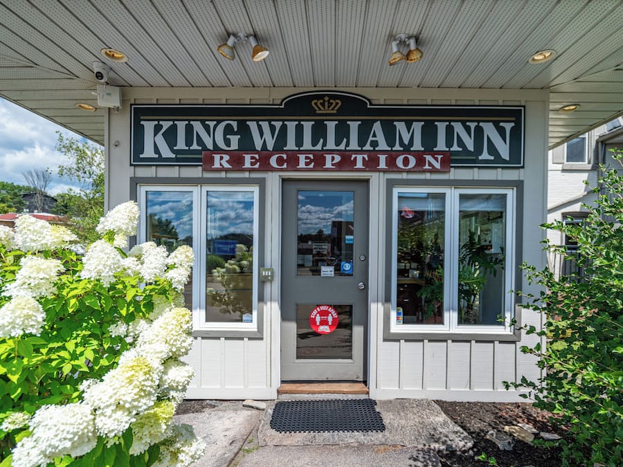 Recepción del King William Inn con entrada despejada, una cámara de seguridad y un letrero que indica un distanciamiento social de 1.8 metros.