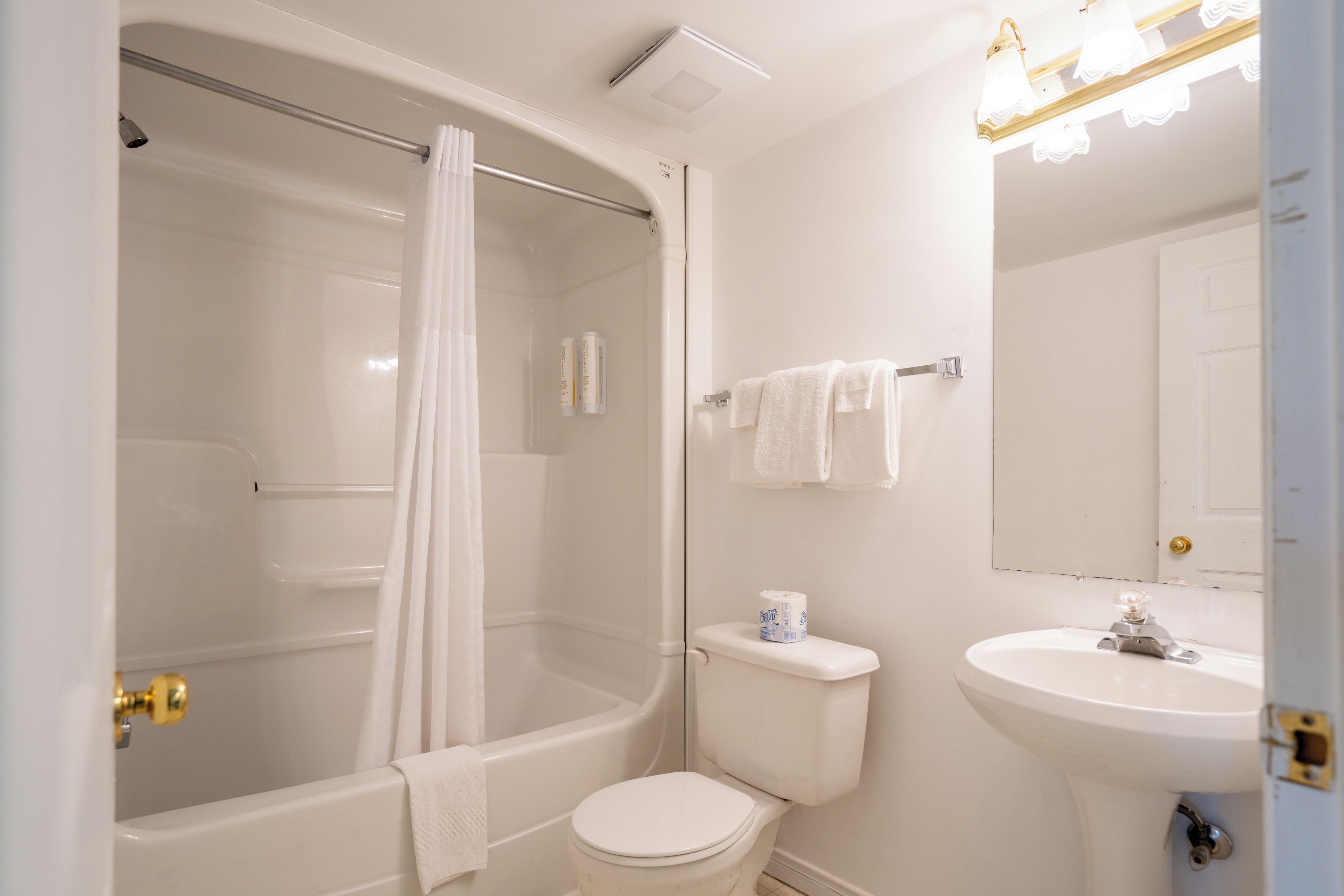 Een badkamer met een bad, toilet, wastafel en douchegordijn.