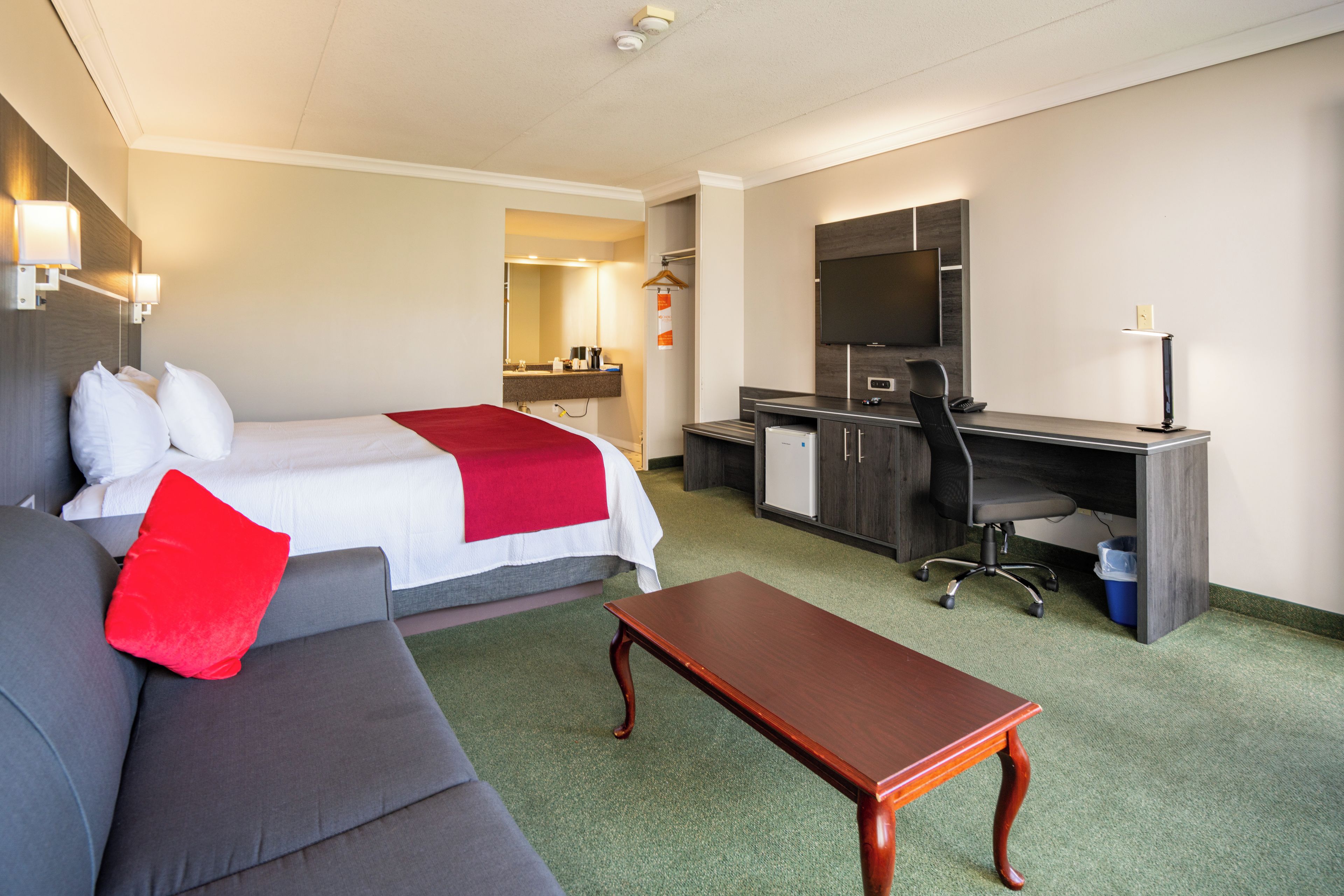 Une chambre d’hôtel avec un lit, un bureau, une chaise, un canapé et une petite table.