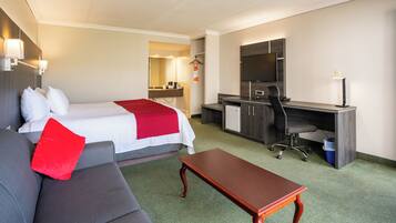 Une chambre d’hôtel avec un lit, un bureau, une chaise, un canapé et une petite table.