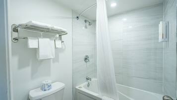 A bathroom with a shower, toilet, and a towel rack with towels.
