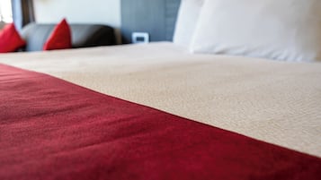 A bed with a red and beige bedspread, a white pillow, and a red pillow.