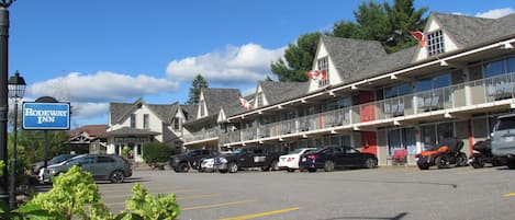 A motel with multiple-story buildings, a parking lot, and a visible sign for the motel.