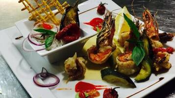 A plate of food with various dishes including grilled shrimp, vegetables, and a waffle.