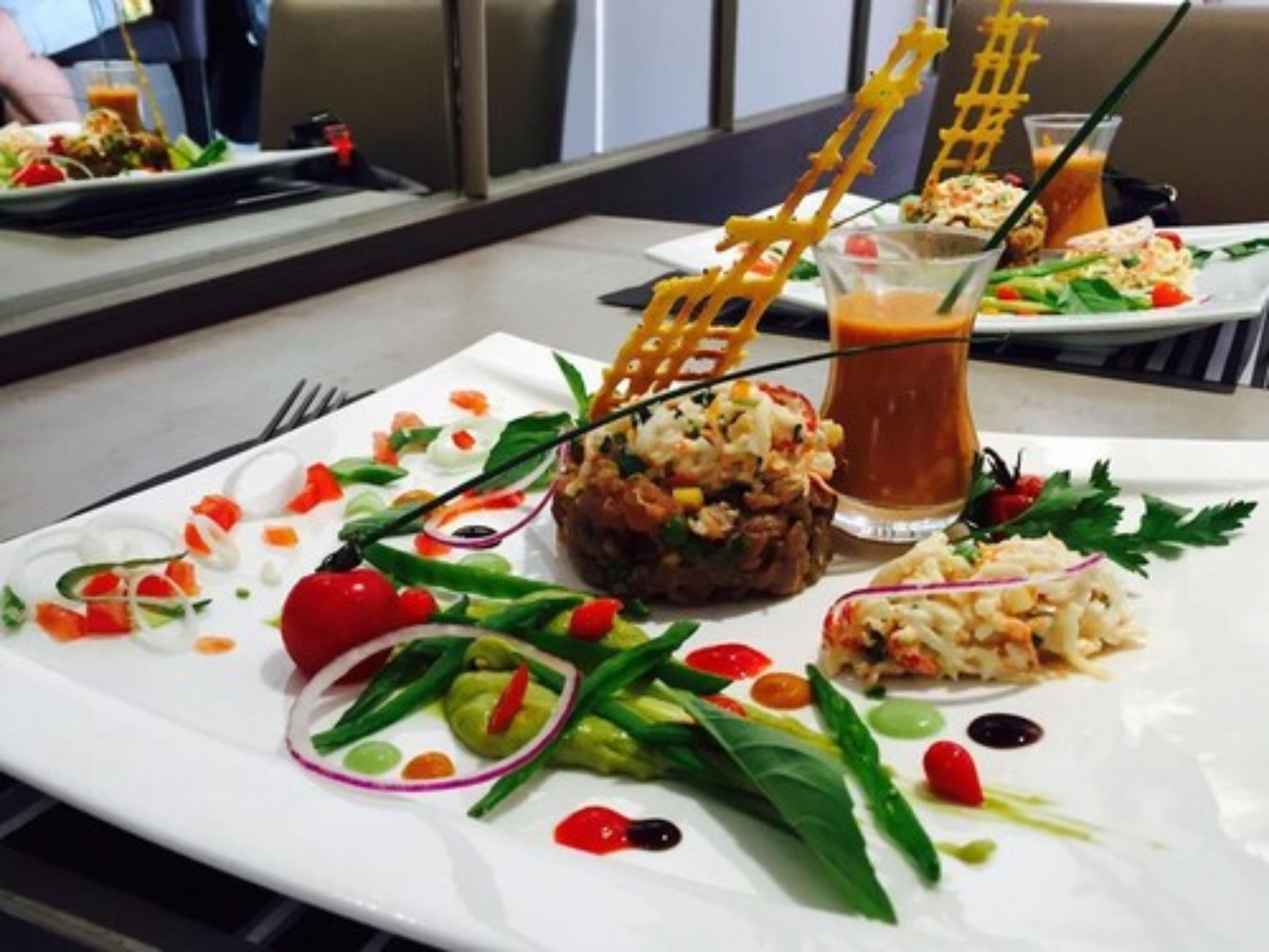 A dining table with a plate of food, a glass of iced tea, and a fork.