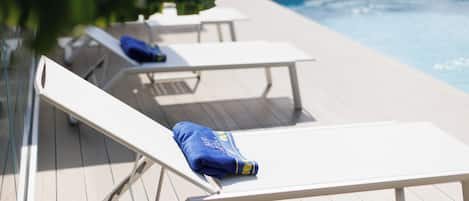 Uma área à beira da piscina com espreguiçadeiras e piscina.