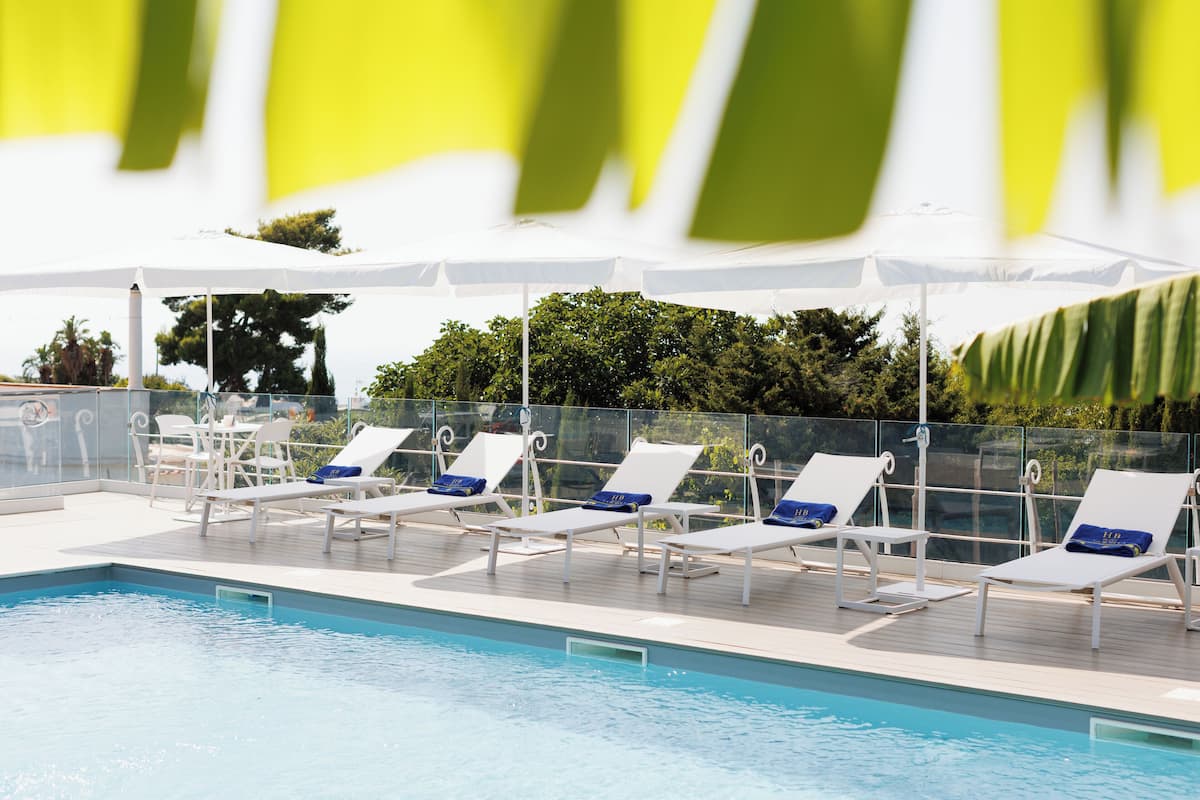 Ein Poolbereich mit weißen Liegestühlen und Sonnenschirmen.