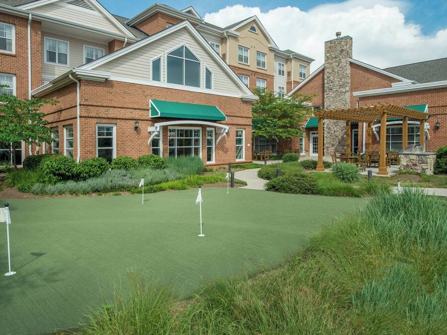 A residential building with a well-maintained lawn and a pergola.