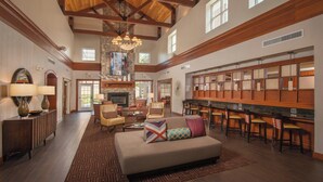 A spacious lobby with a high ceiling, wooden beams, a fireplace, a bar area, and comfortable seating. - Residence Inn by Marriott Dulles Airport At Dulles 28 Centre (Sterling)