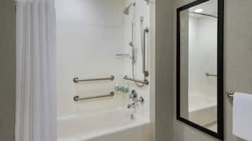 Een moderne badkamer met een witte badkuip, een grote spiegel en handgrepen voor toegankelijkheid.