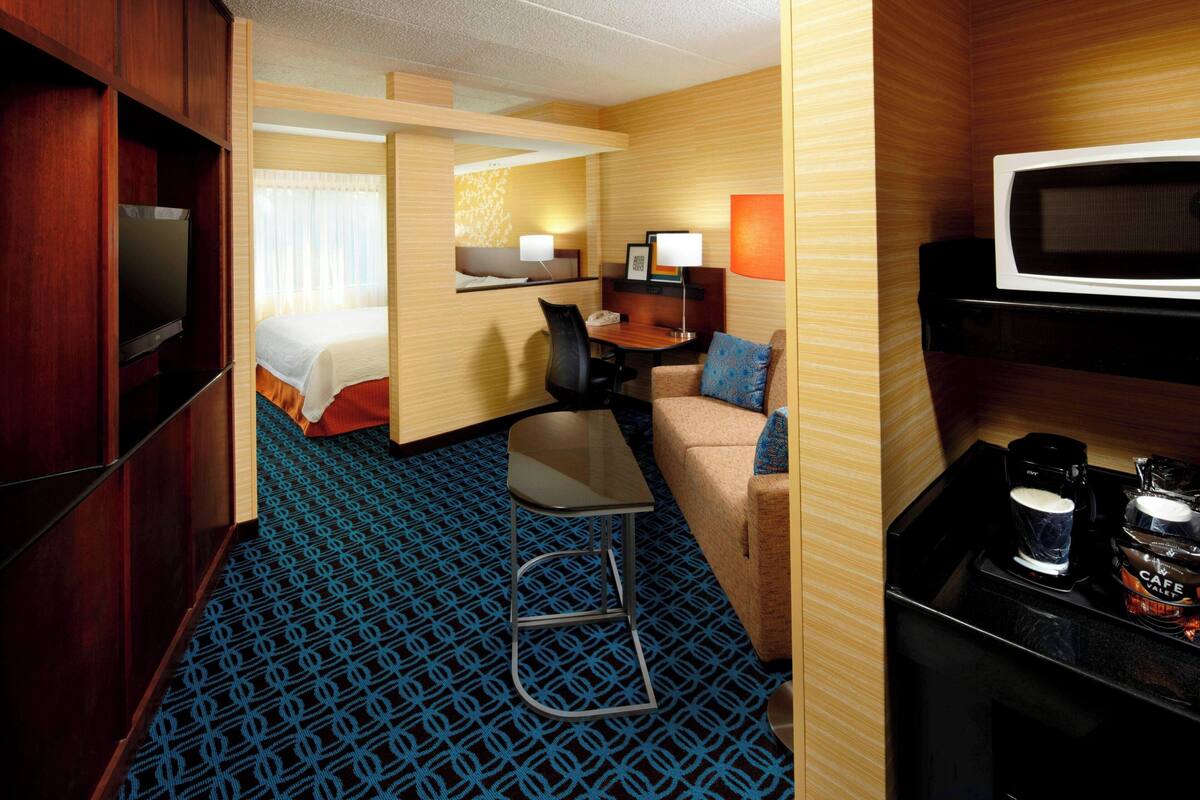 Ein Hotelzimmer mit Bett, Schreibtisch mit Stuhl, Kaffeemaschine und Fernseher.