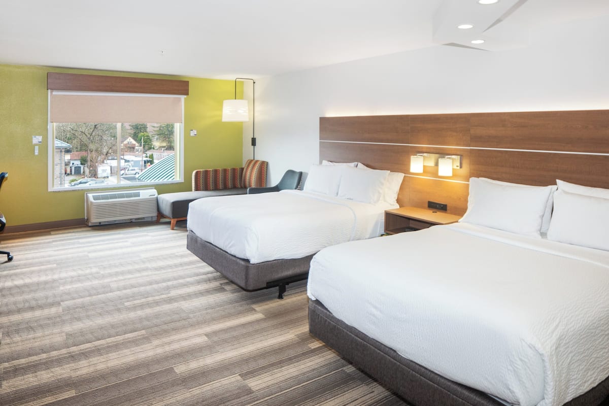 Une chambre d’hôtel avec deux lits, une fenêtre donnant sur un beau paysage, un bureau et une chaise.