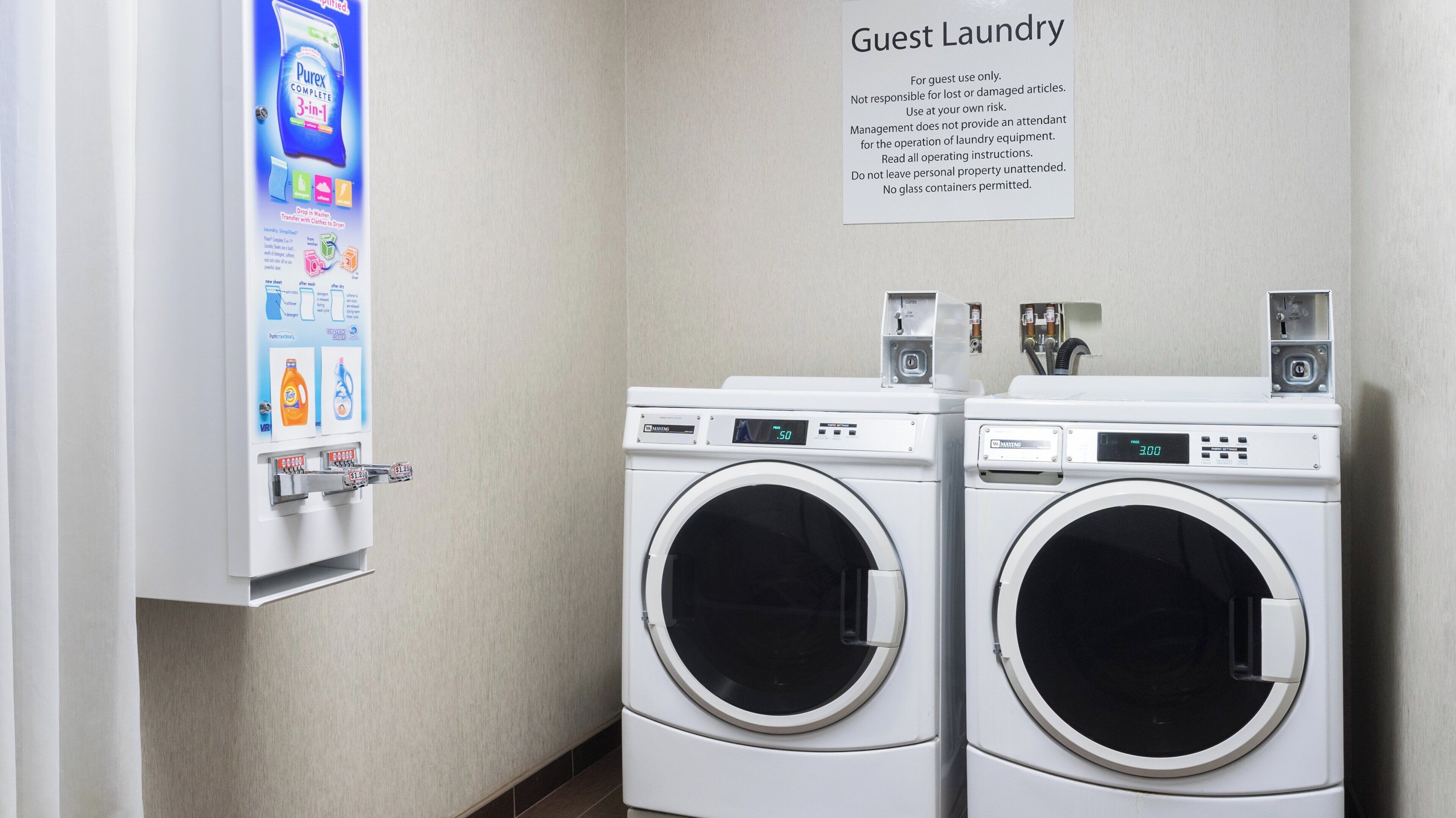 A guest laundry area with two washing machines and a detergent dispenser.