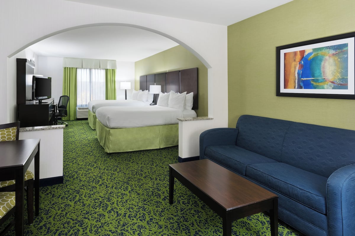 Une chambre d’hôtel avec un lit, un canapé, un bureau et une télévision.
