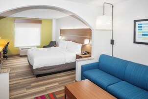 Una habitación de hotel con una cama, un sofá azul, un escritorio y una lámpara.