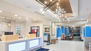 A modern hotel lobby with a reception desk, seating area, and a fireplace.