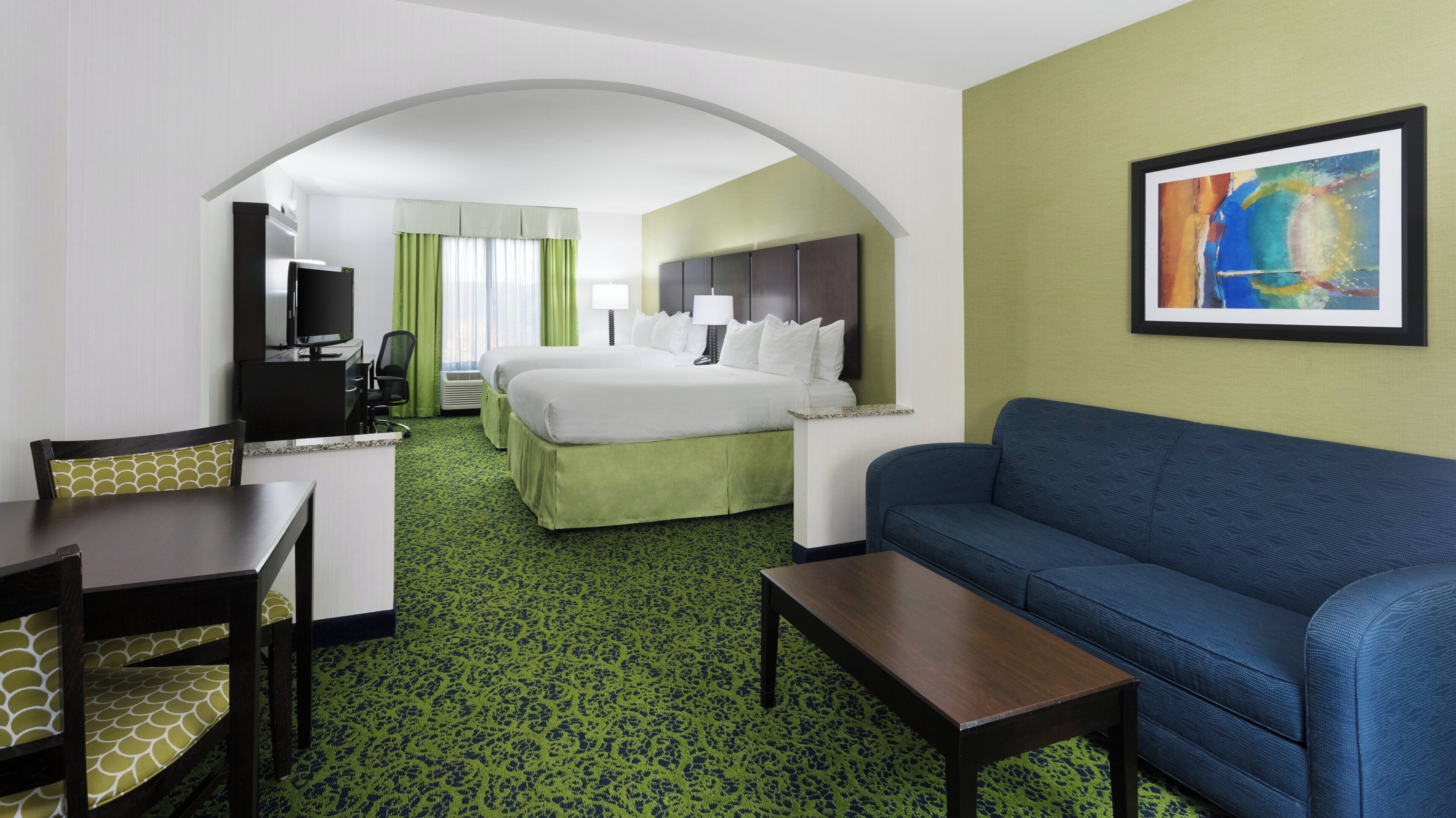 Une chambre d’hôtel avec un lit, un bureau, un canapé et une télévision.