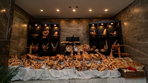 A buffet setup with various food items displayed on tables and shelves, set against a stone wall backdrop.