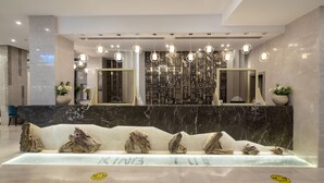 A modern reception area with a marble reception desk, multiple pendant lights, and a decorative wall with hieroglyphs.