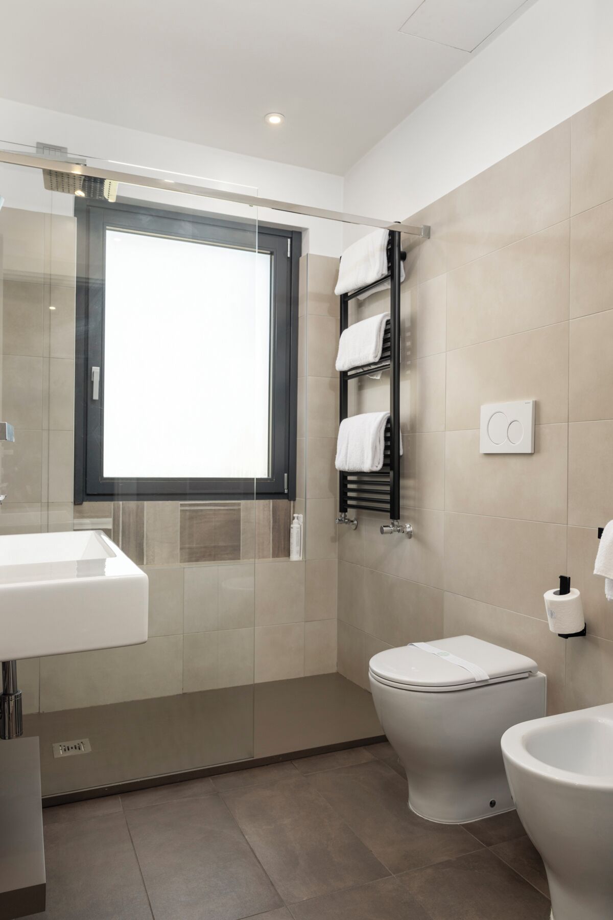 Une salle de bain moderne avec une douche à parois de verre, des toilettes, un lavabo et un porte-serviettes.