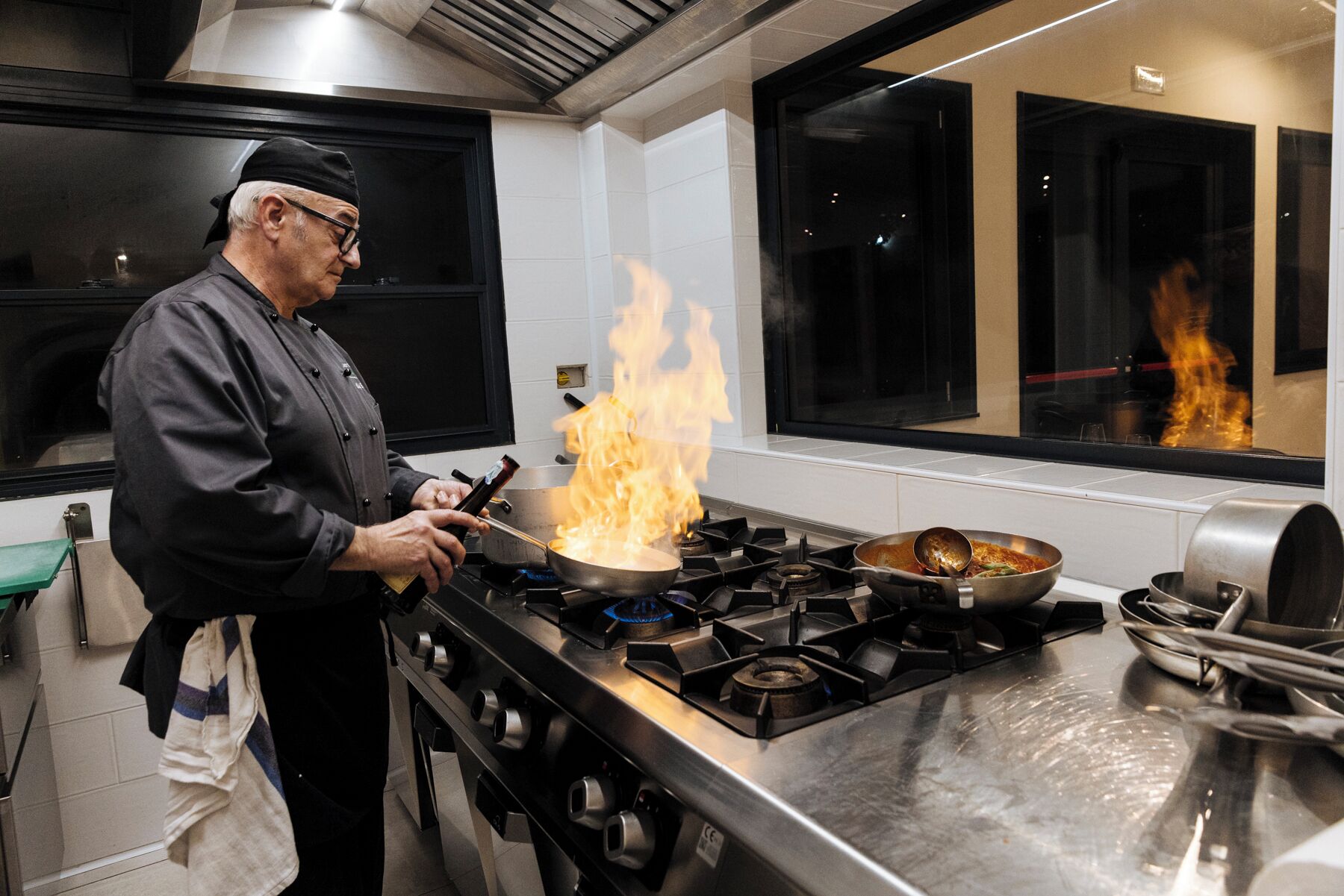 Un chef cocina con llamas sobre un fogón en una cocina moderna.