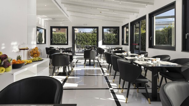 Un comedor moderno con sillas y mesas negras, ventanas amplias y una exhibición de frutas.