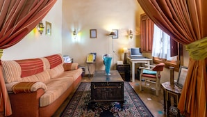 A cozy living room with a sofa, a coffee table, and a desk with a computer. - Abadia Hotel Granada Centro (Granada)