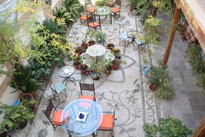 Un patio con mobiliario exterior, plantas en macetas y una fuente central.