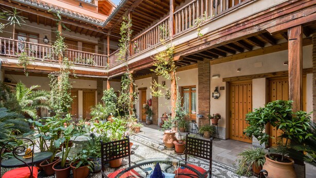 A courtyard with potted plants, outdoor seating, and a wooden balcony. - Abadia Hotel Granada Centro (Granada)