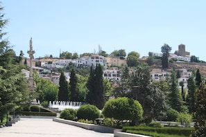 Un pueblo en una ladera con edificios históricos, una fuente y jardines bien cuidados.