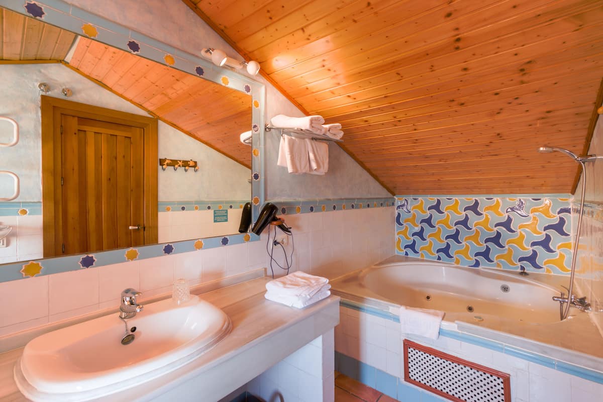 A bathroom with two sinks, a large mirror, wooden ceiling, and patterned tiles.