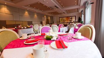 A dining area with tables set for four, each with white plates, red napkins, and white cups.