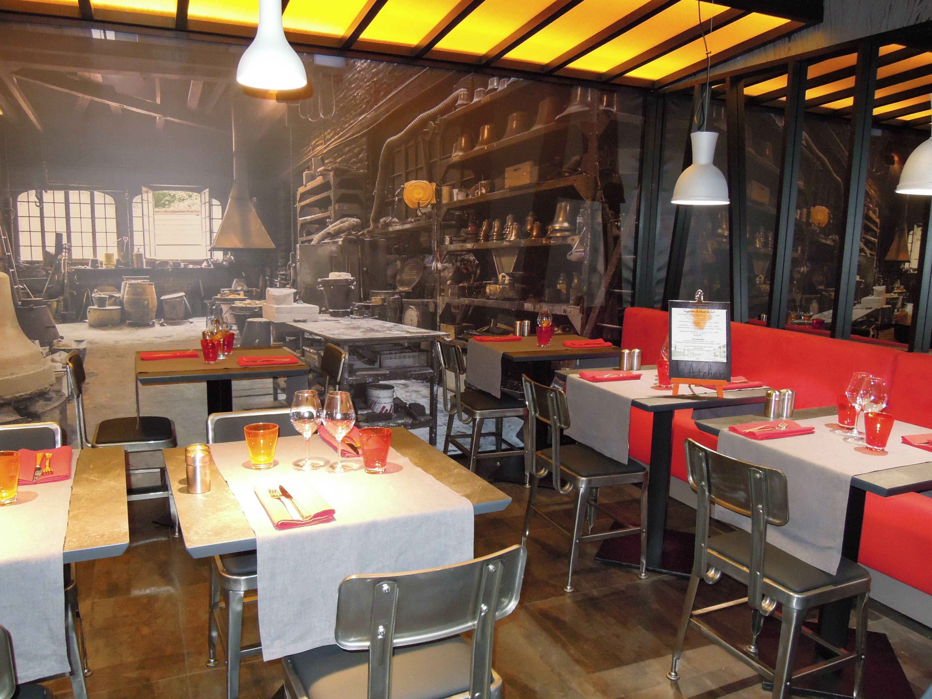 A restaurant interior with tables set for dining, chairs, and hanging pendant lights.