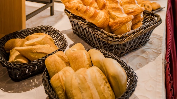 A buffet with baskets of bread and pastries, a toaster, and a coffee machine.