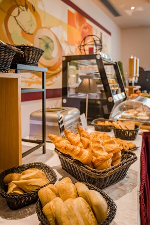Un buffet avec des paniers de pain et de viennoiseries, un grille-pain et une machine à café.