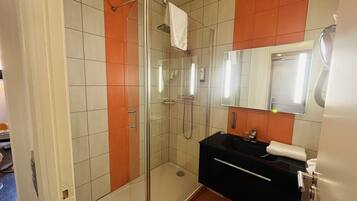 Een moderne badkamer met een douchecabine van glas, een zwarte wastafel en een spiegel erboven.