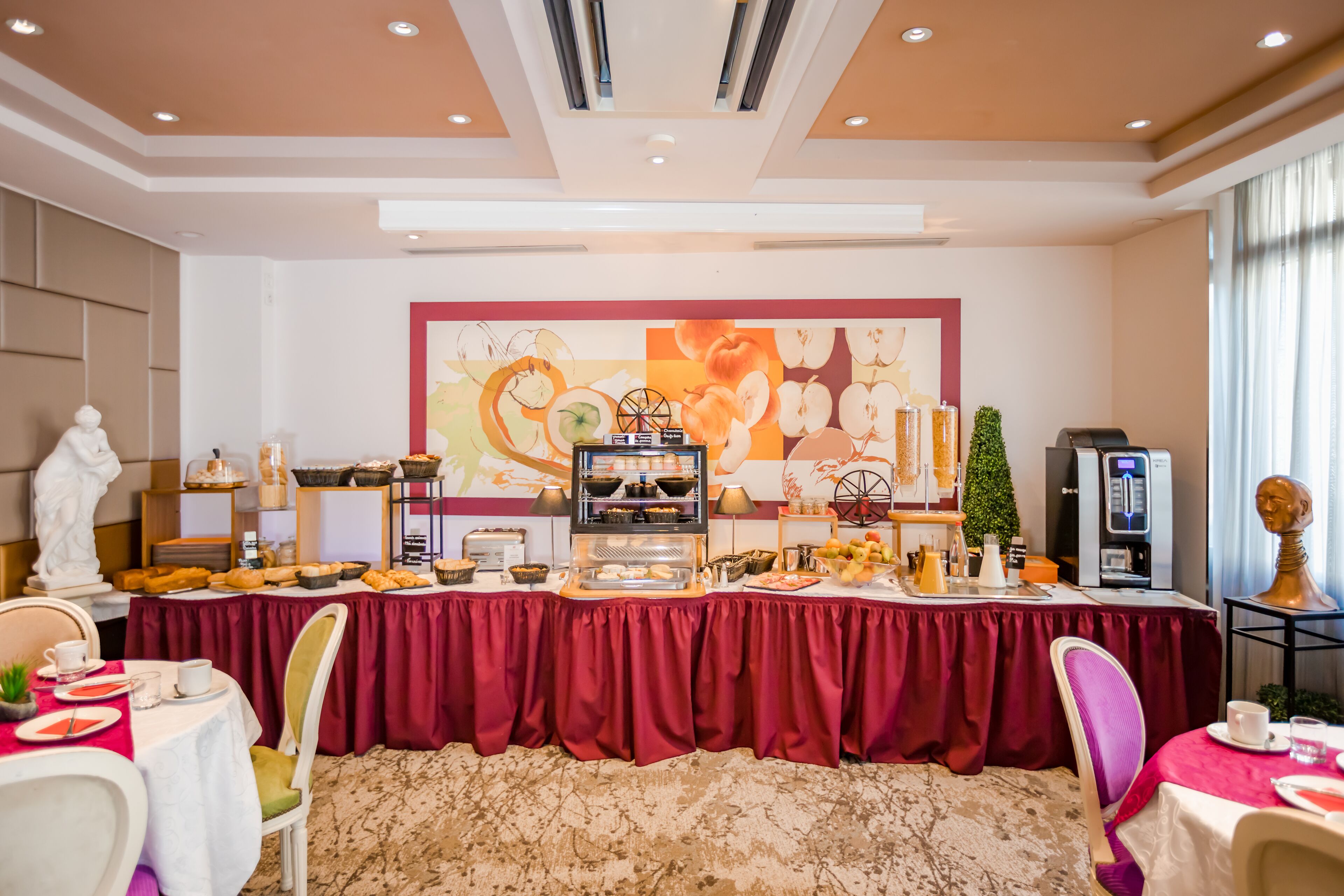 Un buffet de petit-déjeuner proposant une grande variété d’aliments, agrémenté d’un grand tableau décoratif et d’une statue.