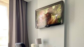 Une chambre d’hôtel équipée d’un bureau, d’une chaise, d’une télévision, d’une lampe, d’un téléphone et d’une poubelle.