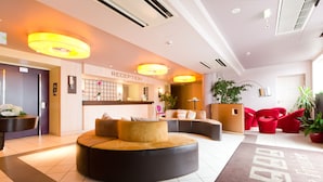 A modern reception area with a reception desk, a seating area with round ottomans, and a reception sign.