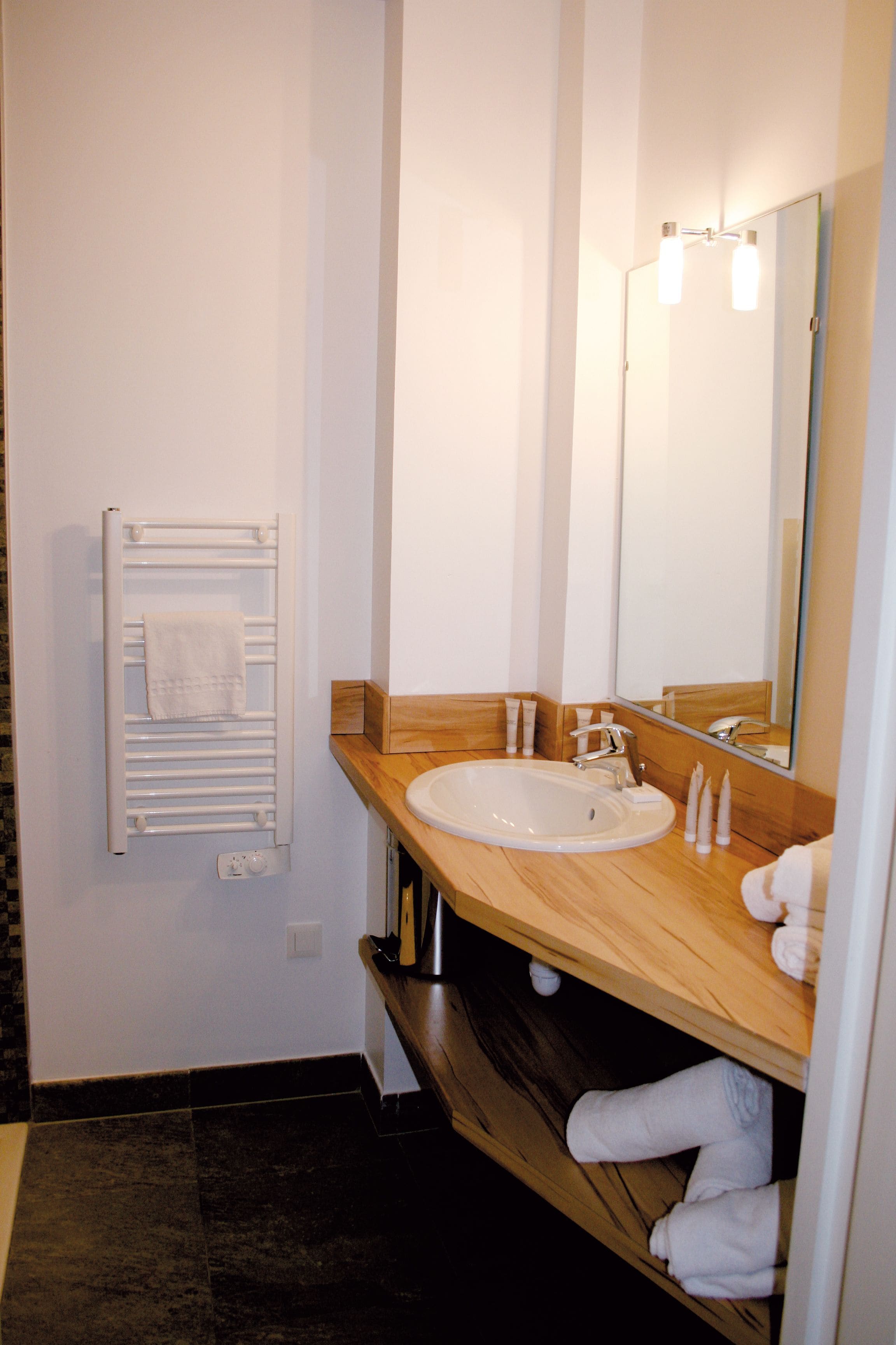 A bathroom with a white sink, a mirror, and a towel rack.