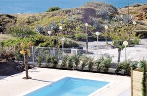 A pool area with a clear view of the ocean, surrounded by a fence and various plants. - Thalacap Résidence (Agde)