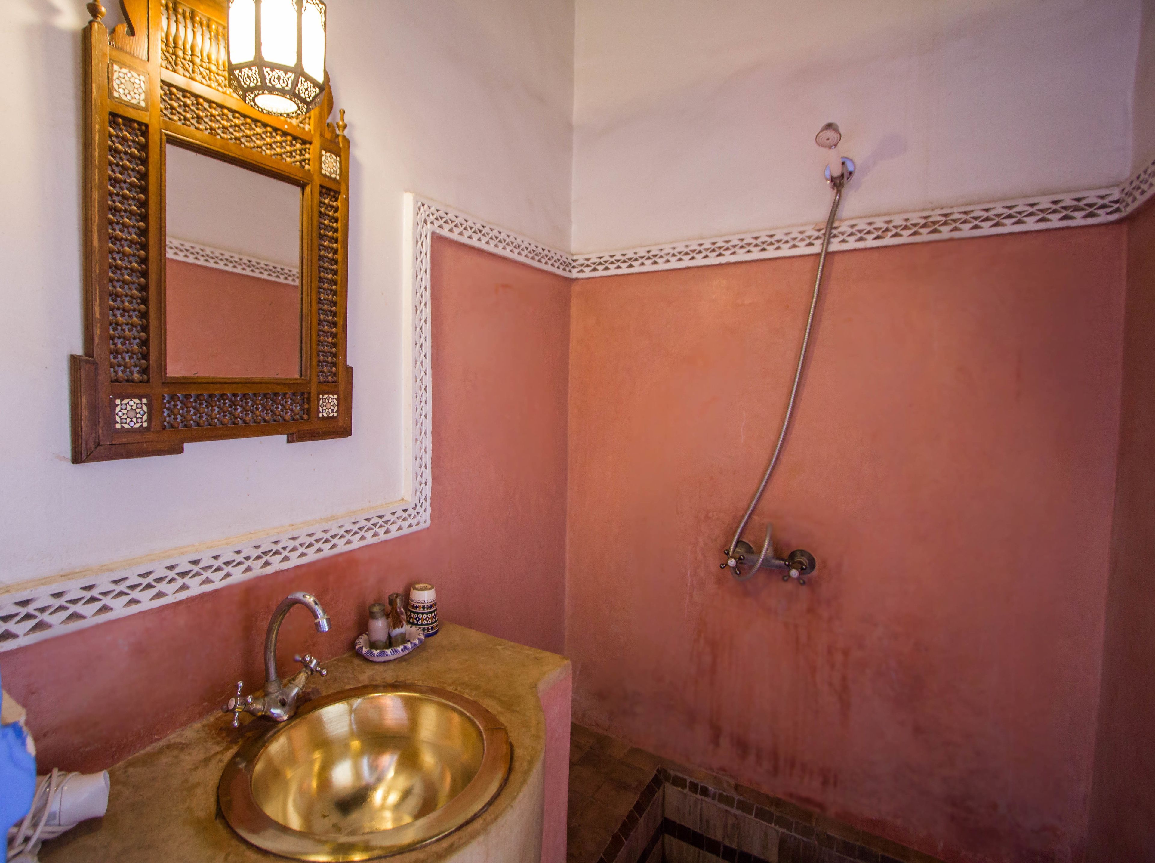 A bathroom with a sink, mirror, and shower.